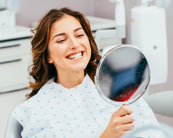 woman examining her smile in a mirror