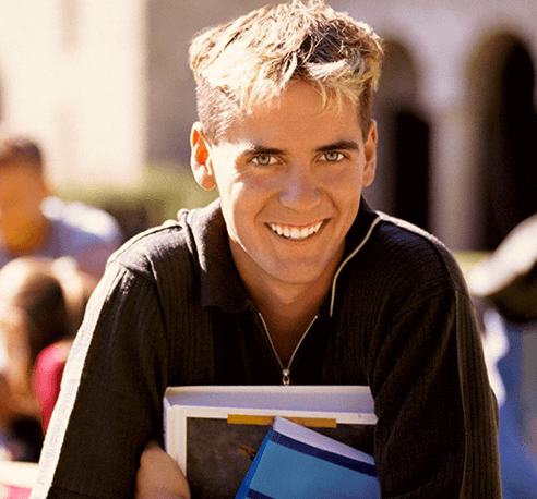 boy holding books and smiling