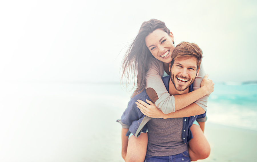 cosmetic dentistry, beautiful smiling couple on the beach